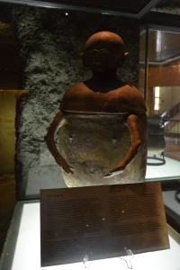 This is unique and the only intact anthropomorphic burial jar with two arms, nipples, navel and male sex organ on the body that is found in an archaeological context. The head is unpainted and with perforations on the lid that show side parting of the hair. Its lips are colored with red hematite and accented with an incised design. It also has two ear lugs on the lower half of the urn.